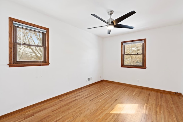 spare room with light wood-style floors, baseboards, visible vents, and ceiling fan