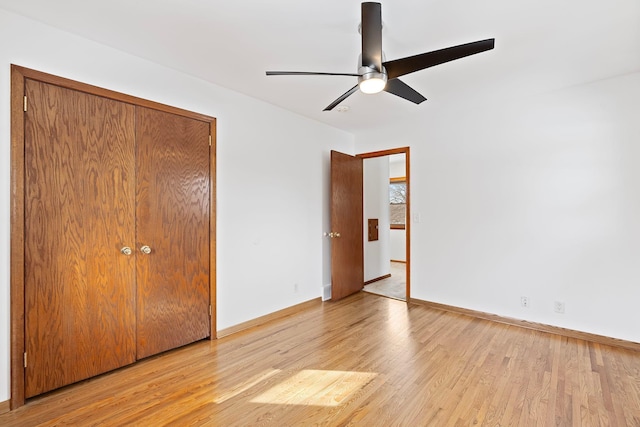 unfurnished bedroom featuring light wood-type flooring, a ceiling fan, baseboards, and a closet