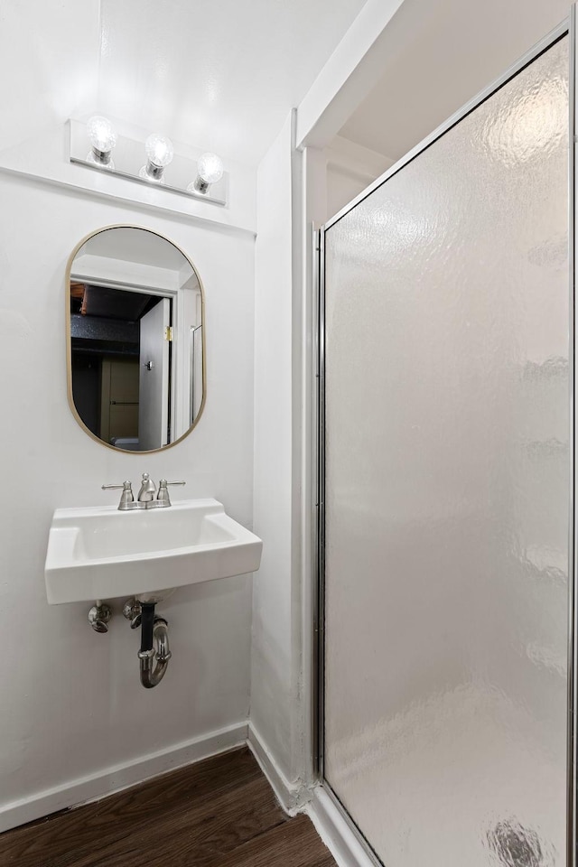 bathroom featuring a stall shower, a sink, baseboards, and wood finished floors