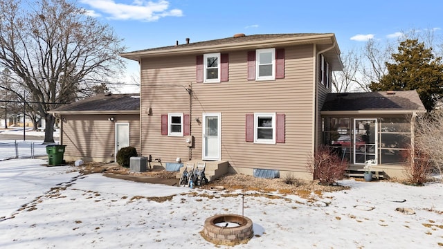 snow covered house featuring entry steps, a sunroom, a fire pit, and central AC unit