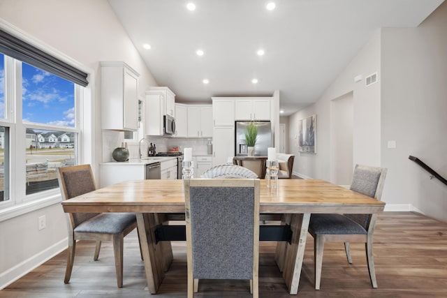 dining room with baseboards, vaulted ceiling, wood finished floors, and recessed lighting