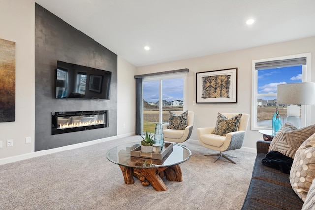 carpeted living area with recessed lighting, baseboards, vaulted ceiling, and a glass covered fireplace