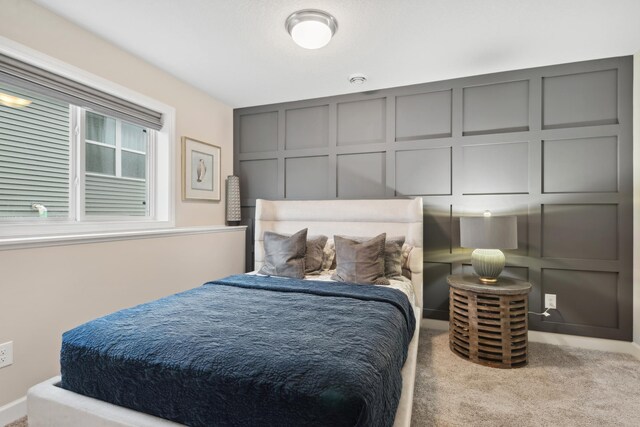 bedroom with light colored carpet and a decorative wall