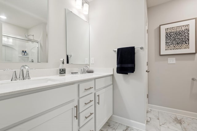 bathroom with marble finish floor, double vanity, a sink, and baseboards