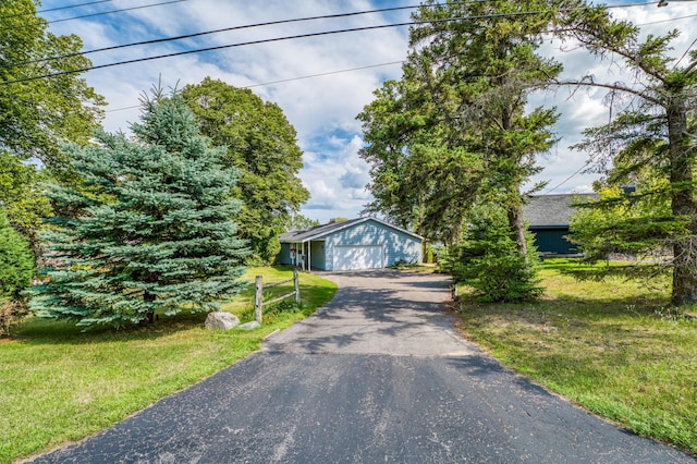 view of front of home featuring a garage, driveway, a front lawn, and an outdoor structure