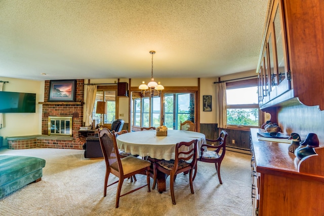 dining area with a textured ceiling, a chandelier, light carpet, a fireplace, and wainscoting