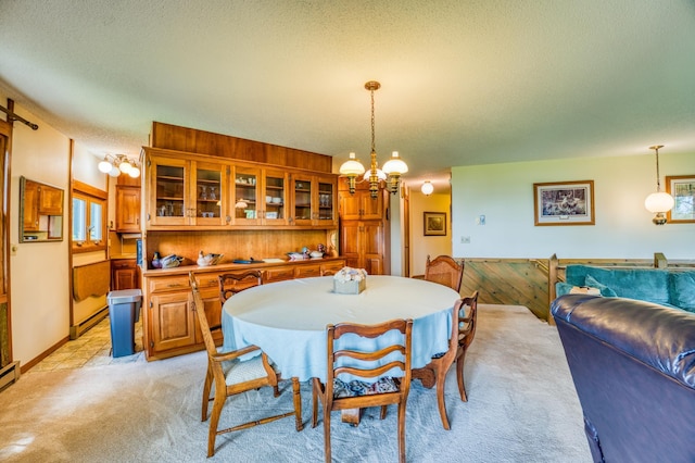 dining room featuring light colored carpet, a textured ceiling, baseboard heating, and an inviting chandelier