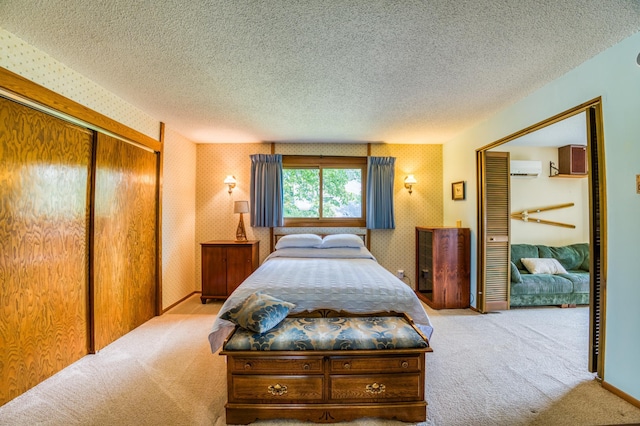 bedroom with a textured ceiling, a wall unit AC, light carpet, a closet, and wallpapered walls