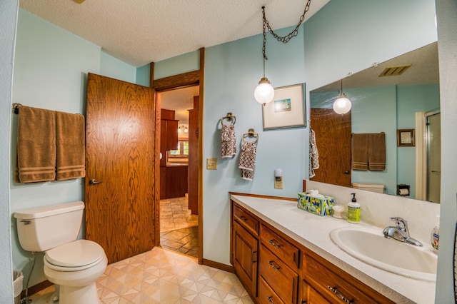 full bathroom with baseboards, visible vents, toilet, a textured ceiling, and vanity