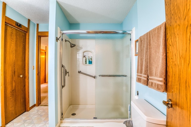 full bathroom featuring a stall shower, baseboards, a textured ceiling, and toilet