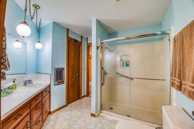 full bath featuring a closet, a shower stall, vanity, a textured ceiling, and baseboards