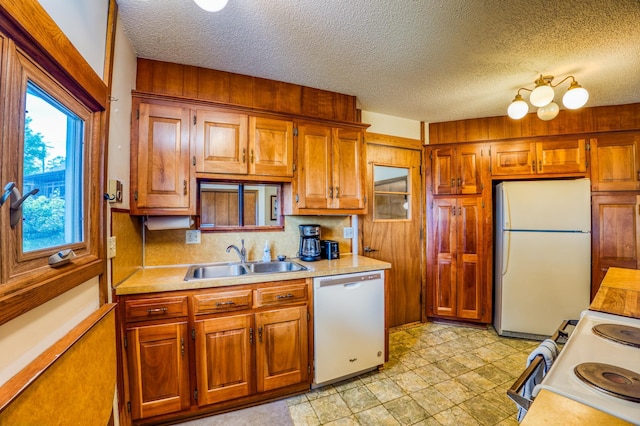 kitchen with light countertops, white appliances, a sink, and brown cabinets