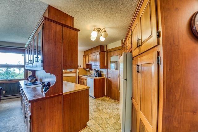 kitchen featuring a textured ceiling, white appliances, light countertops, brown cabinets, and an inviting chandelier