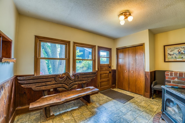 entryway with wainscoting, wooden walls, and a textured ceiling