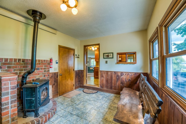 foyer entrance featuring a wood stove, a wainscoted wall, and wooden walls