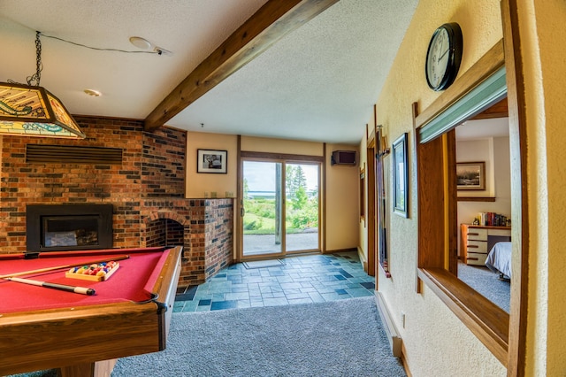 rec room with a brick fireplace, a textured ceiling, beamed ceiling, and light colored carpet