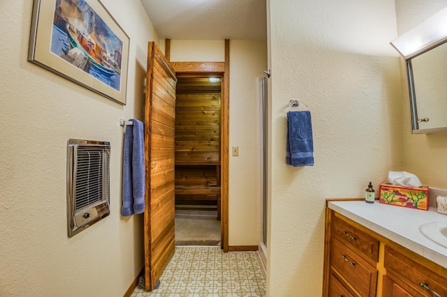 full bath with baseboards, tile patterned floors, heating unit, vanity, and a shower stall