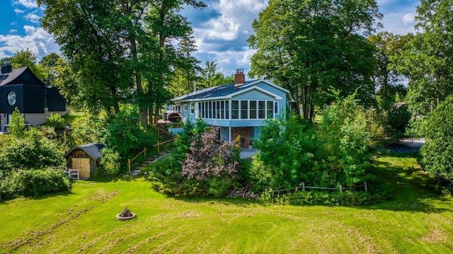 view of yard featuring a sunroom, stairway, a storage unit, and an outdoor structure