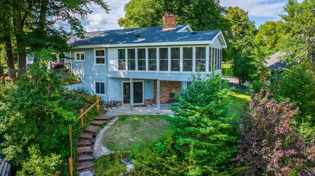 rear view of house featuring a lawn, a patio, a chimney, and a sunroom