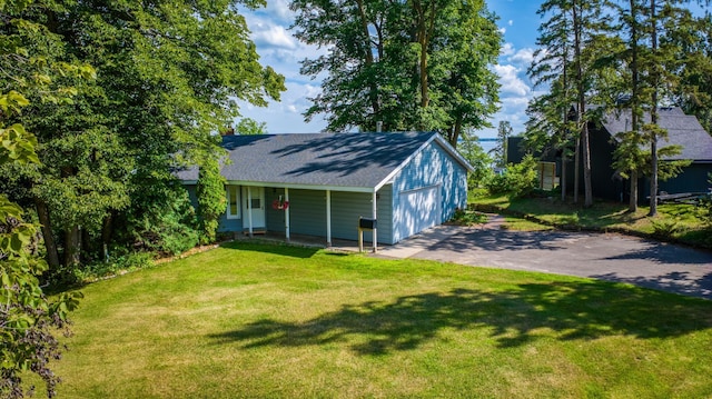 view of front of home featuring a garage, a front yard, roof with shingles, and driveway