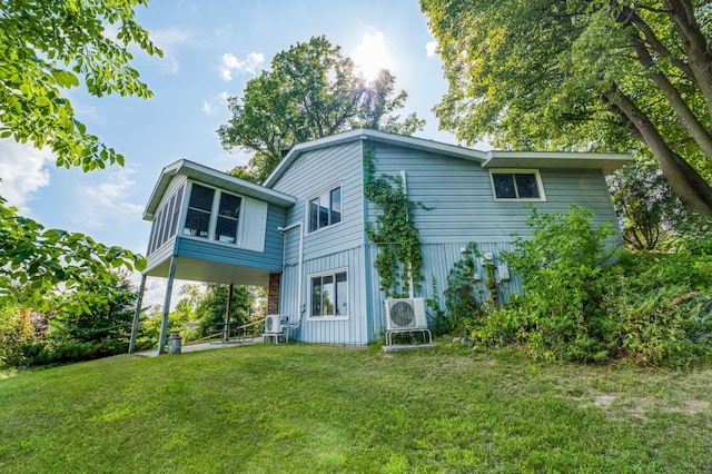 rear view of house with ac unit and a yard