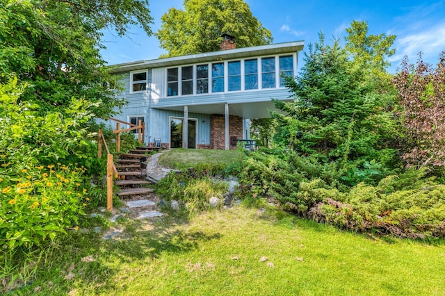 view of front of property with stairs, a chimney, and a front lawn