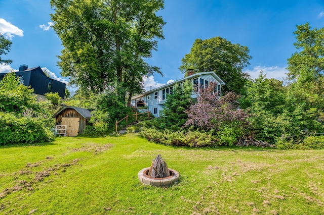 view of yard with an outdoor fire pit, an outbuilding, and a shed