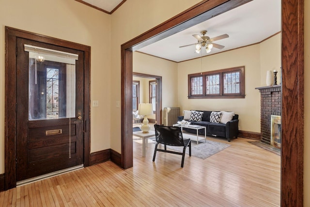 foyer entrance featuring light wood finished floors, ornamental molding, and a wealth of natural light