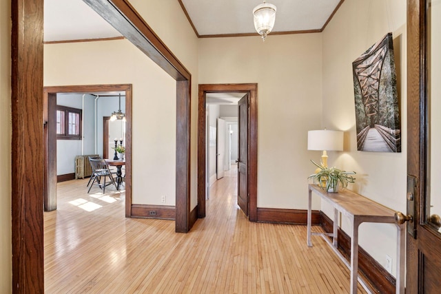 interior space featuring radiator, light wood-style floors, baseboards, and crown molding