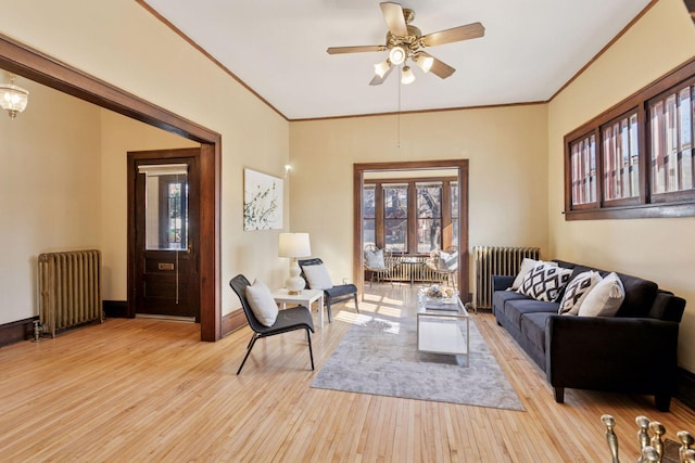 living area featuring light wood-style floors, radiator, ornamental molding, and baseboards