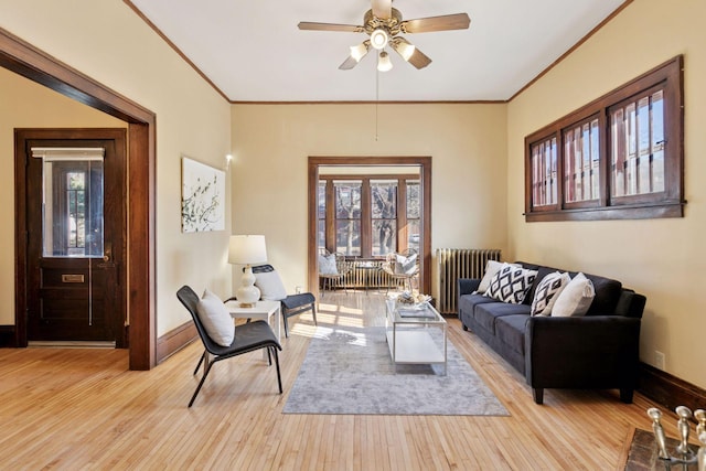 living room featuring ornamental molding, light wood-style floors, baseboards, and radiator