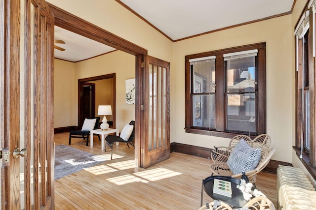 entryway featuring light wood finished floors, baseboards, ornamental molding, and a wealth of natural light