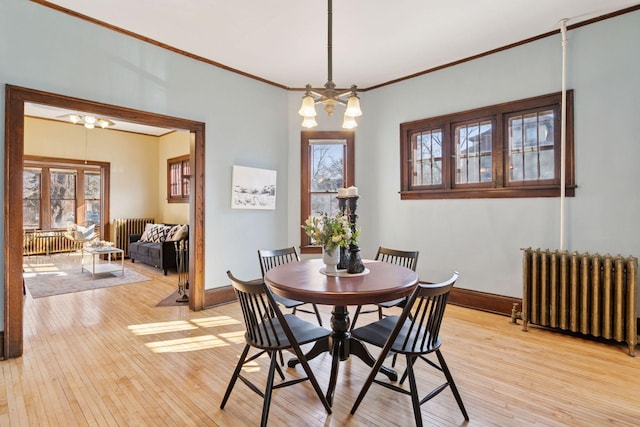 dining area featuring radiator, light wood-style flooring, a chandelier, and baseboards