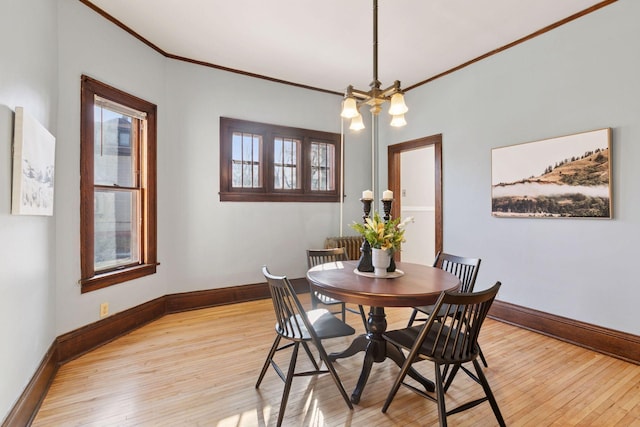 dining space with ornamental molding, light wood-style flooring, and baseboards