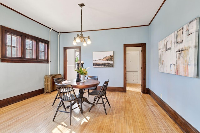 dining area with light wood-style flooring, crown molding, baseboards, radiator heating unit, and an inviting chandelier