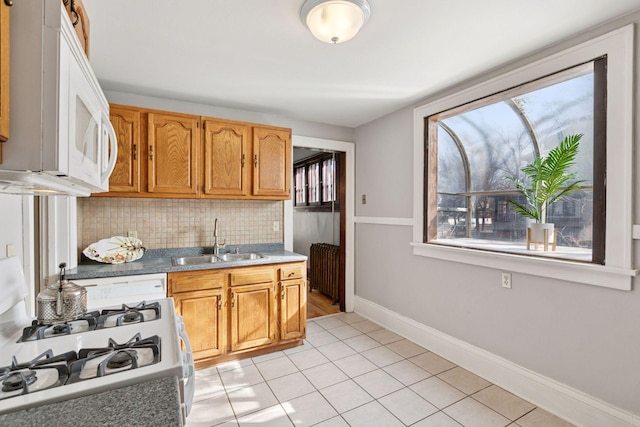 kitchen with white appliances, tasteful backsplash, a wealth of natural light, and a sink