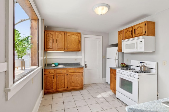 kitchen featuring white appliances, brown cabinets, baseboards, and light tile patterned floors