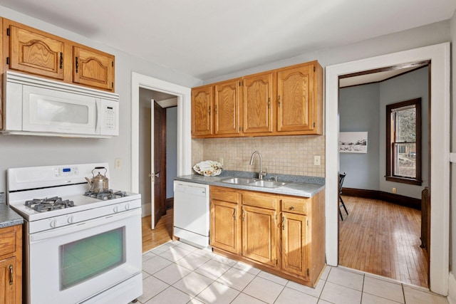 kitchen featuring light tile patterned flooring, white appliances, a sink, baseboards, and decorative backsplash