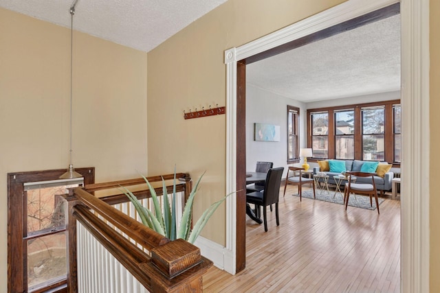 interior space with light wood-type flooring, a textured ceiling, and an upstairs landing