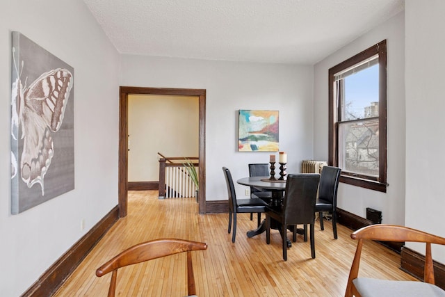 dining space with light wood-style floors, radiator heating unit, and baseboards