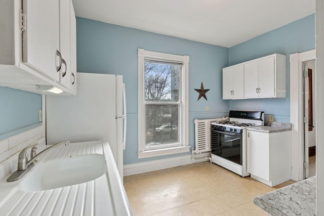 kitchen featuring a sink, baseboards, white cabinets, light countertops, and gas range gas stove