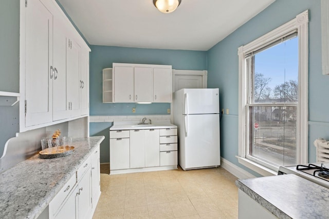 kitchen with open shelves, light countertops, freestanding refrigerator, white cabinets, and baseboards