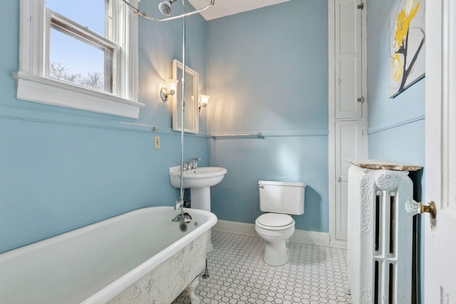 bathroom featuring baseboards, toilet, a soaking tub, radiator, and tile patterned floors