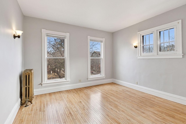 unfurnished room with baseboards, hardwood / wood-style flooring, and radiator