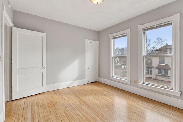 empty room featuring wood-type flooring, baseboards, and a textured ceiling