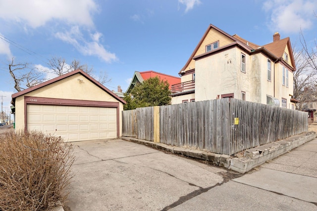 view of property exterior with a chimney, fence, an outdoor structure, and stucco siding