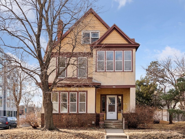 view of front of property featuring entry steps, brick siding, fence, and stucco siding