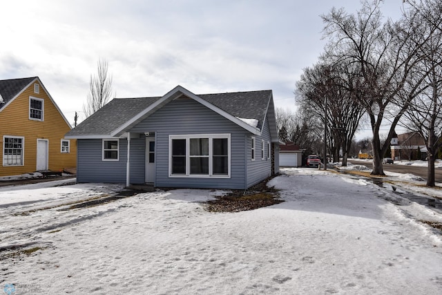 view of front of property featuring a garage, roof with shingles, and an outdoor structure