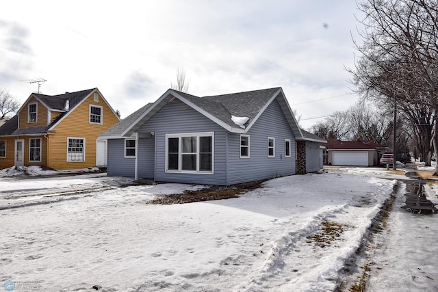 view of front of property featuring a garage, a shingled roof, and an outdoor structure