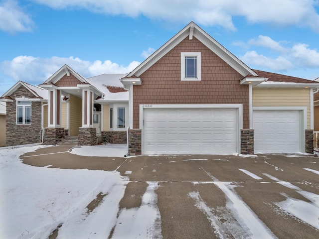 craftsman-style house with a garage, stone siding, and driveway